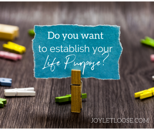 Colorful clothespins on a table. One it upright, holding a blue piece or paper that reads: "Do you want to establish your life purpose?"